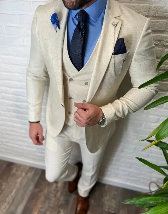 Homme en costume trois pièces crème avec chemise bleue