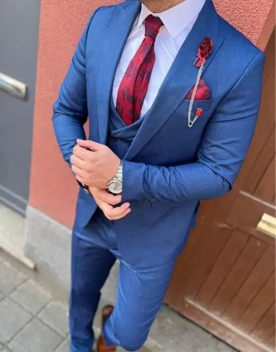 Homme en costume bleu avec cravate rouge et montre