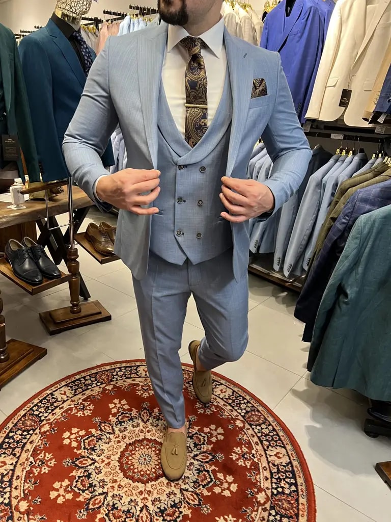 Homme portant un costume bleu clair avec gilet et cravate.